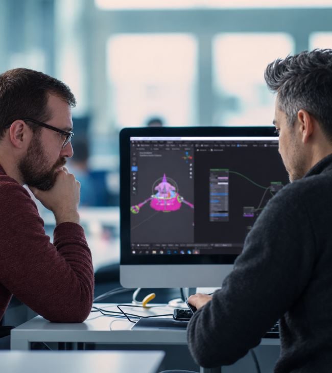 Two members of the SLIDEFACTORY team reviewing 3D work on a monitor